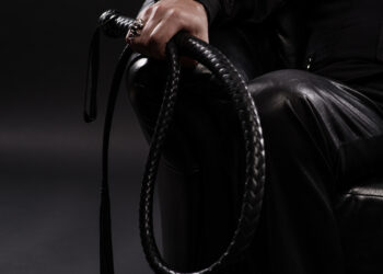 male hand holding black leather whip